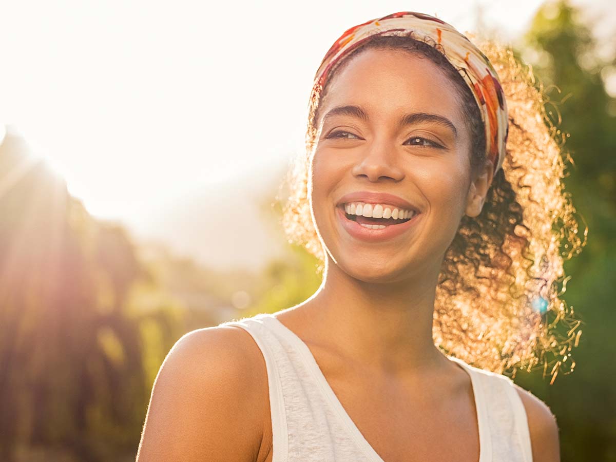 Smiling woman outdoors in sunlight.